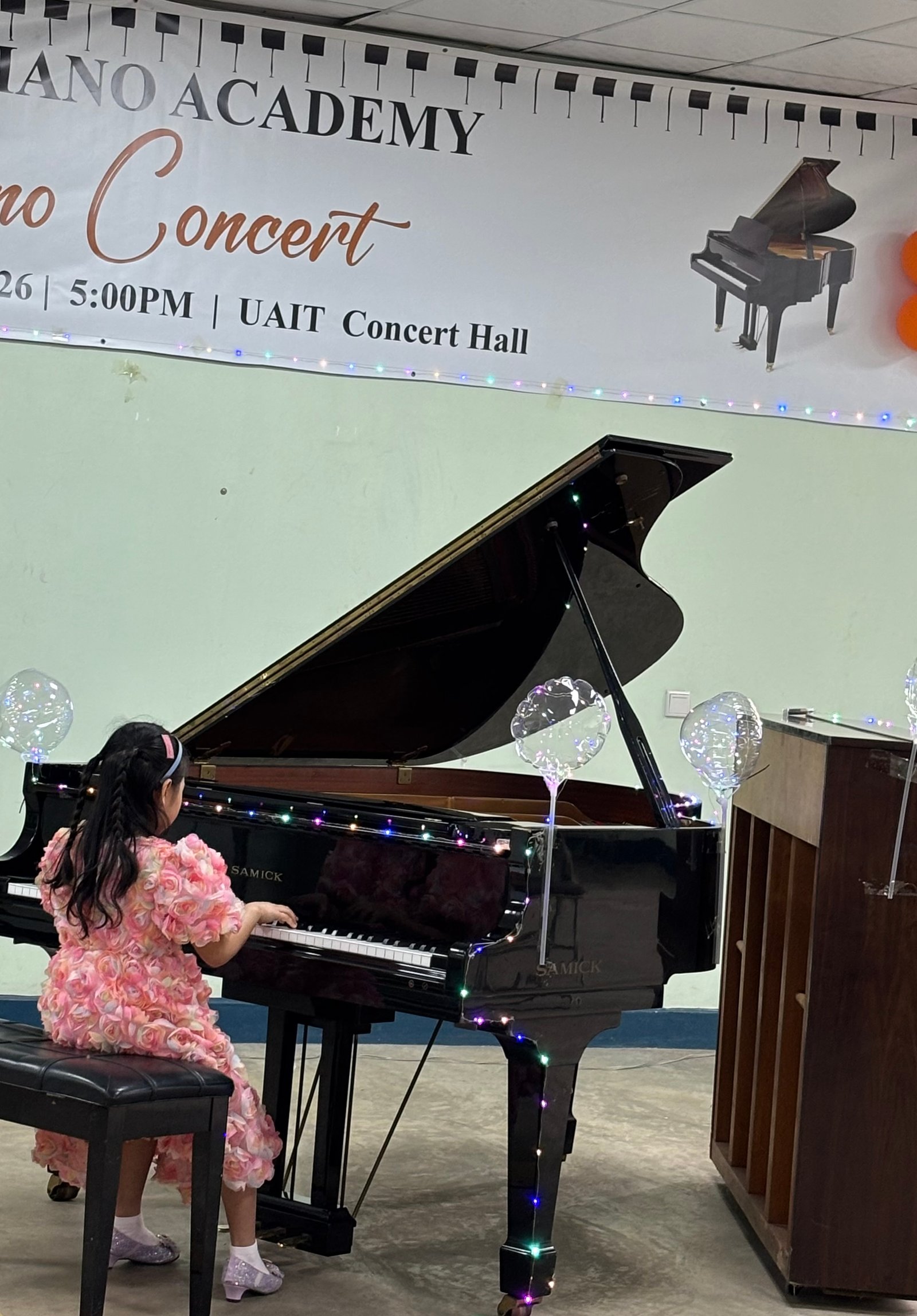 Young girl in pink dress performing on the grand piano