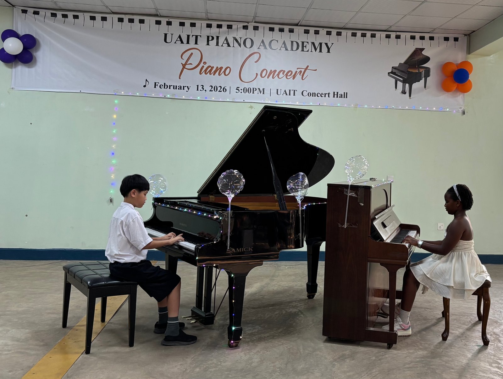 Two students performing a duet on grand and upright piano